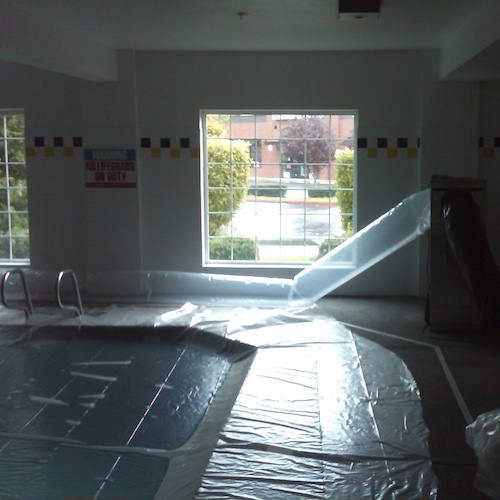 A swimming pool at the Best Western Hotel in Vancouver WA during a Water Damage Restoration, with the pool covered with plastic to create a containment barrier.