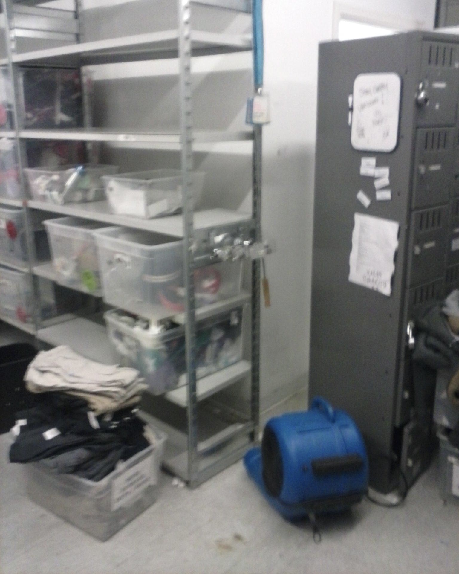 Grey employee lockers, and shelving, with a grey tile floor, a blue centrifugal fan drying after water damage at the Vancouver Mall in Vancouver Washington