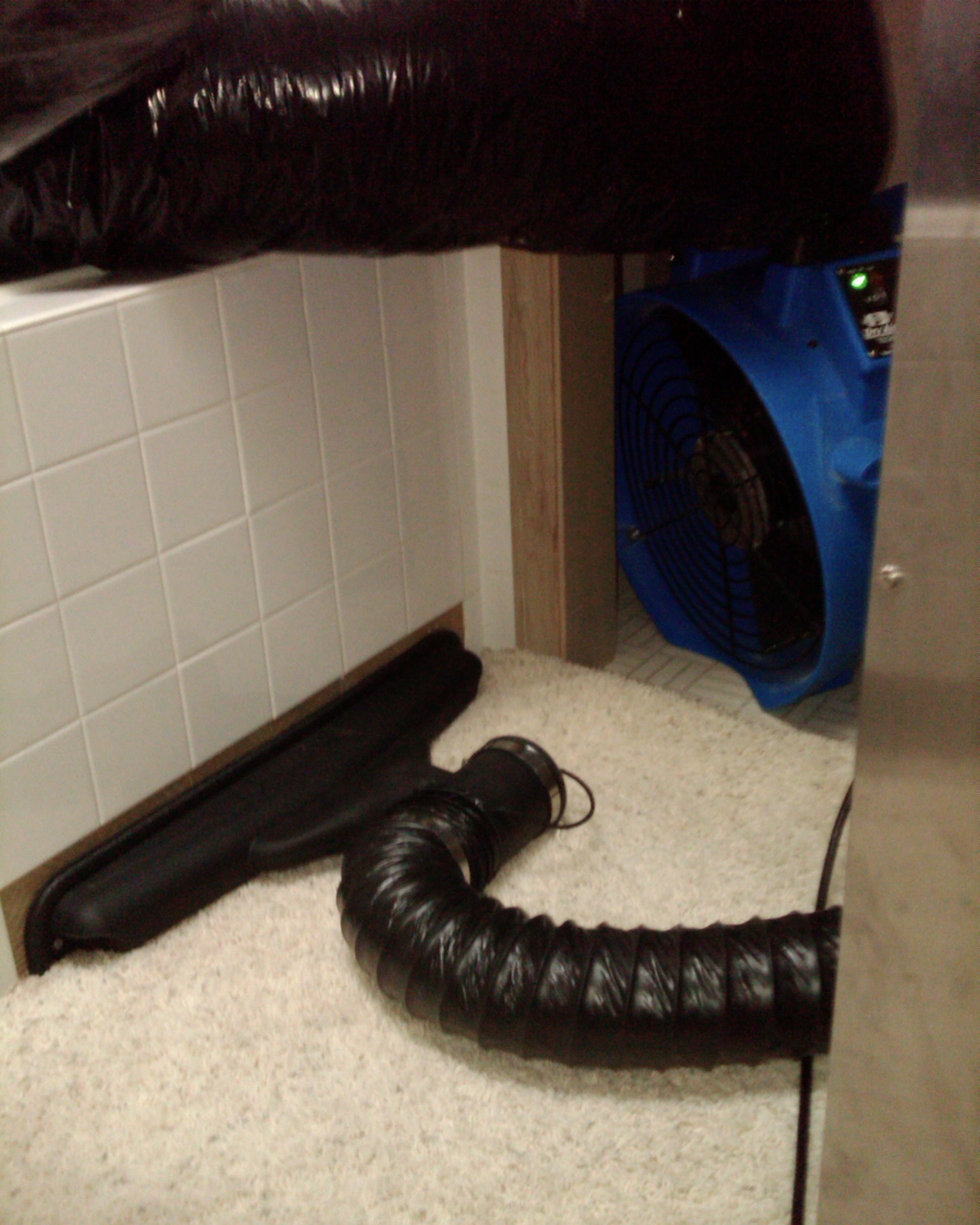 Image of a blue axial fan and a black wall injection drying system forcing dry warm air into a tiled wall at 3111 Se Balboa Drive in Vancouver WA 98683