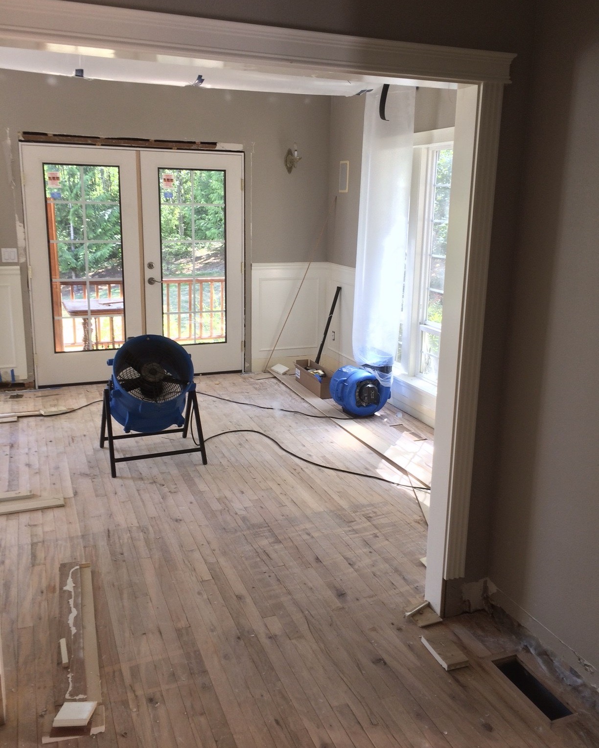 Image of a room with French doors and unfinished Harwood floors during a water damage restoration project at 31213 NE 69th St Camas, WA 98607