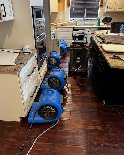 Four blue centrifugal fans, and one commercial dehumidifier drying out kitchen cabinets at a water damage at 31020 NW 51st Ave Ridgefield, WA 98642