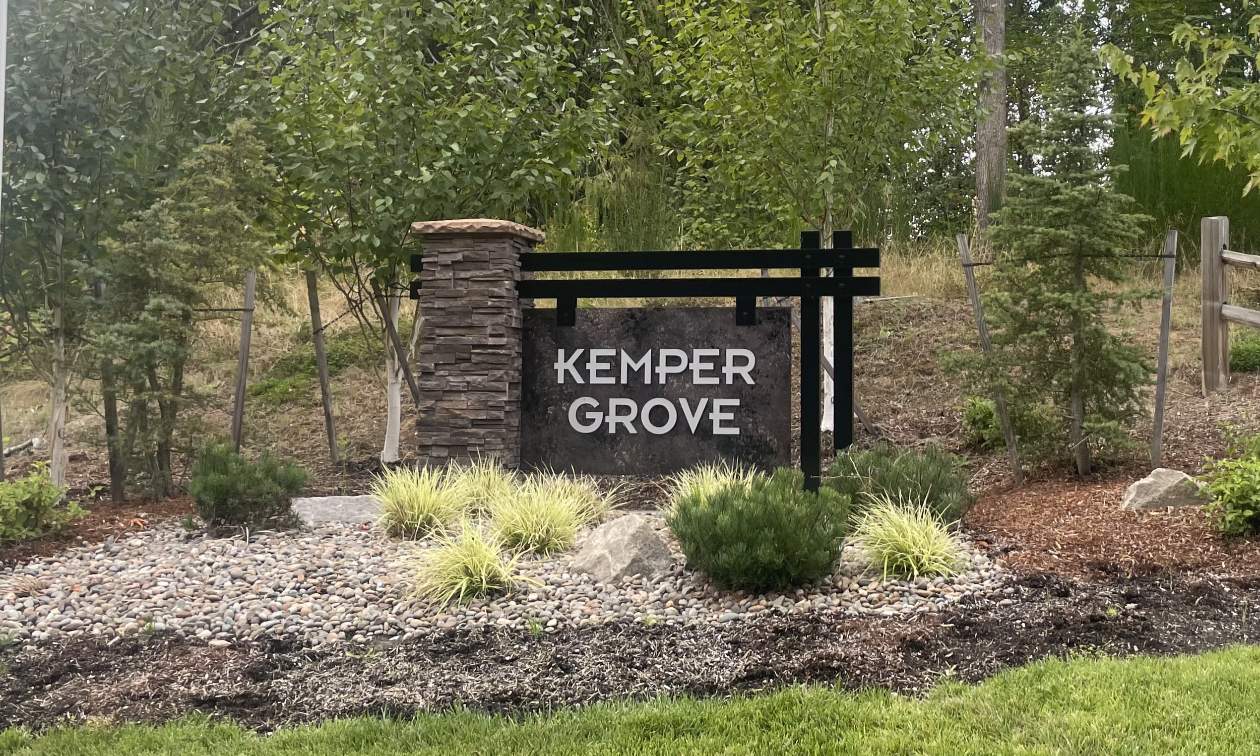 Entrance sign to Ridge at Kemper Grove, a neighborhood in Ridgefield Washington.  Made out of stone, metal and surrounded by landscaping shrubs