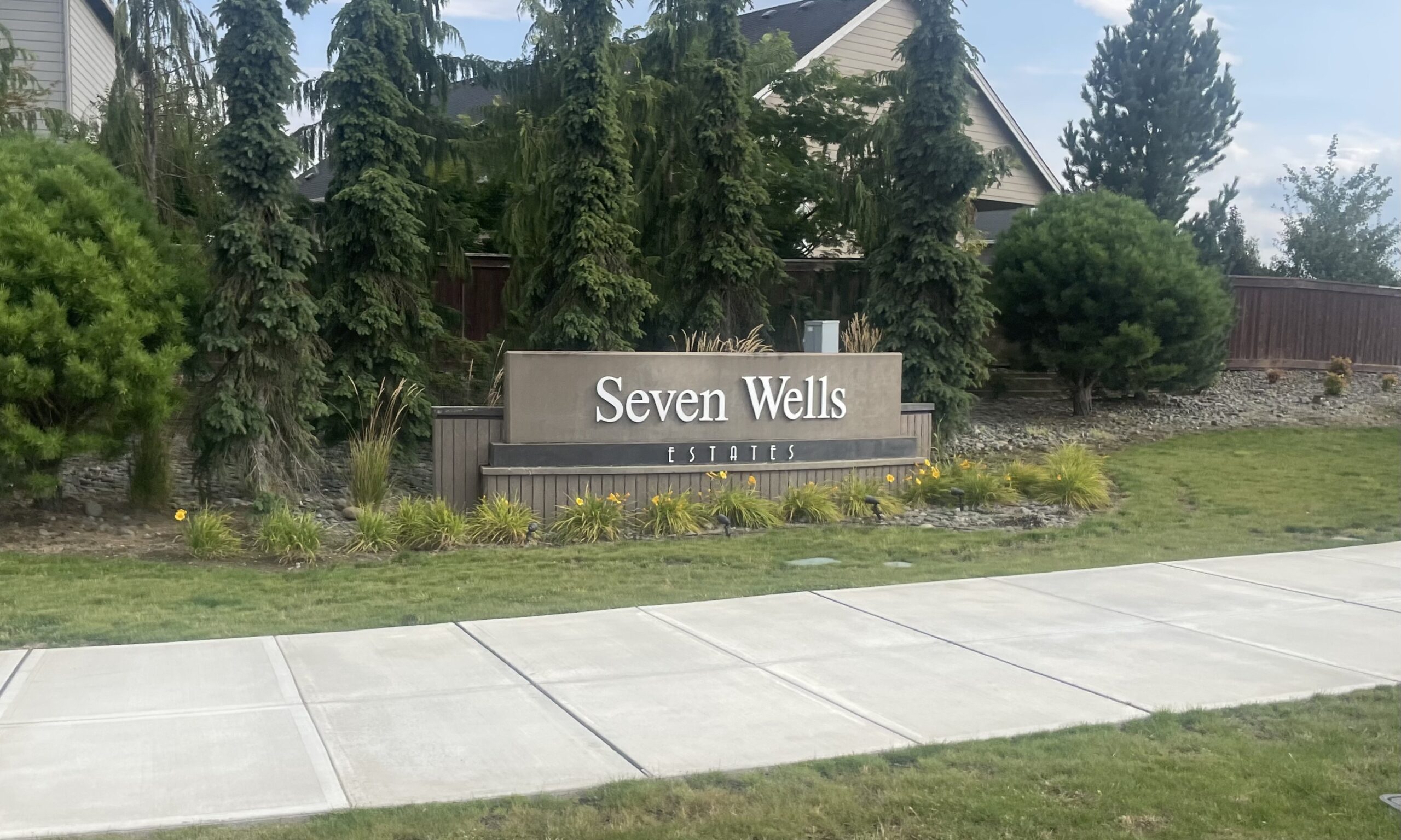 The Reserve at Seven Wells neighborhood entrance sign in Ridgefield Washington with landscaping around it, and a sidewalk in front.