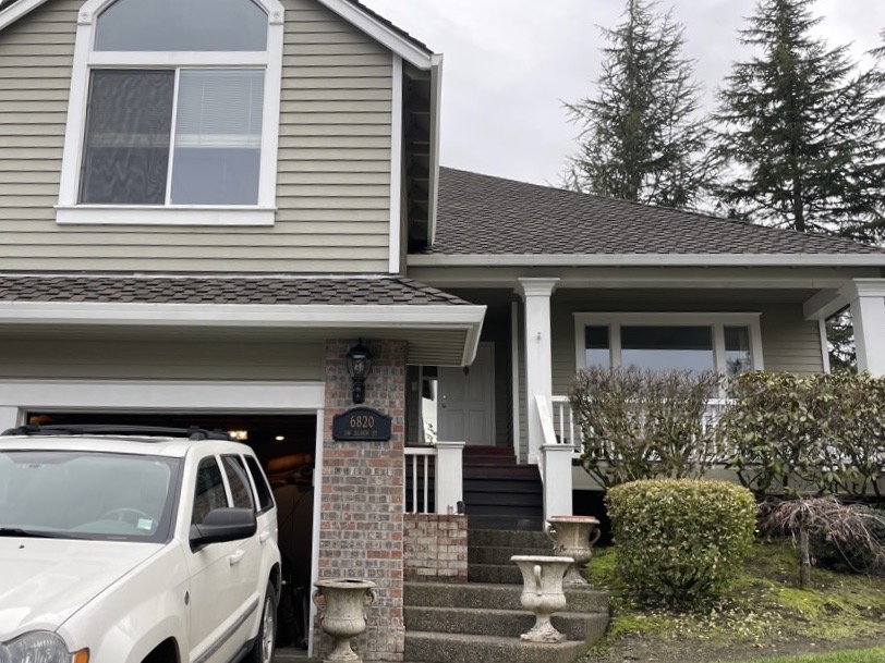 A suburban home in the Portland Metro and SW Washington area with beige siding and a white car in the driveway